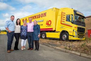 The W.S. Dennison family, from left to right: James, Nikki, Maureen, William and Pamela standing in front of the company's yellow and red truck and trailer which has a special 40th anniversary logo added